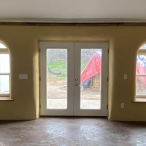 South living room wall w/ rounded openings, natural plasters and earthen floor