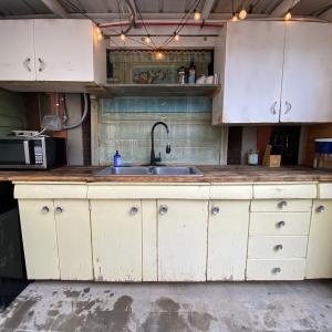 Outdoor kitchen for studio features salvaged cabinets and backsplash