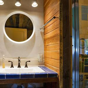 Salvaged cedar planks, plumbing fixtures, and tiles combine with clay plaster to provide visual interest and mitigate excess humidity in the bathroom.
